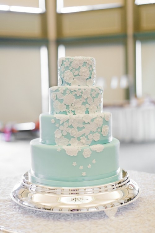 a mint blue wedding cake with white sugar blooms all over the cake, here and there, is a delicate and vintage-inspired idea for a wedding done in pastels