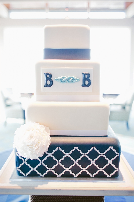 a bold nautical wedding cake with white and navy tiers, with Moroccan patterns, monograms and ribbons is a stylish idea for a seaside wedding