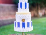 a bright and whimsical wedding cake with striped blue and white tiers, a couple of tan tiers and white lace around them plus a vintage brooch is wow