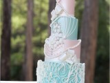 a pastel wedding cake with aqua and light pink tiers, sugar beads, pearls and embellishments, ribbons and other decor for a glam vintage-inspired wedding