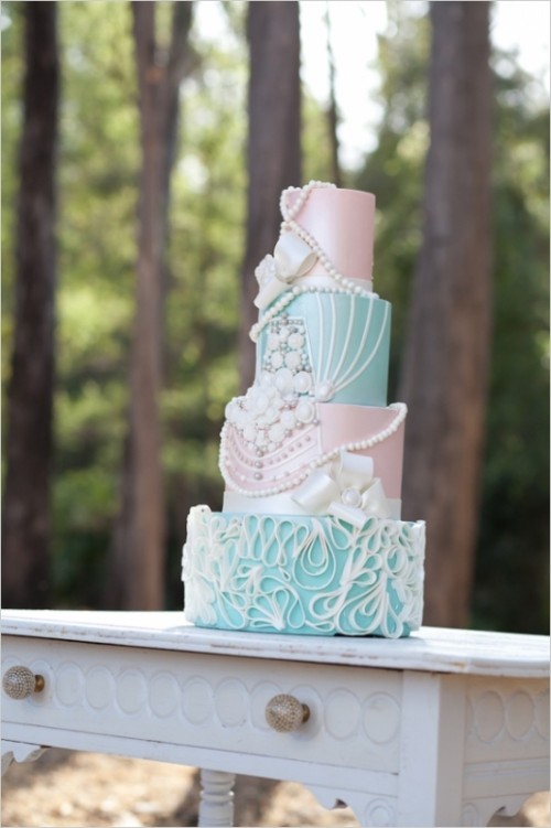 a pastel wedding cake with aqua and light pink tiers, sugar beads, pearls and embellishments, ribbons and other decor for a glam vintage-inspired wedding
