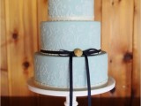 a light blue wedding cake with white patterns, a white sugar bloom on top, a black ribbon with a bow is a chic idea for a vintage-infused wedding