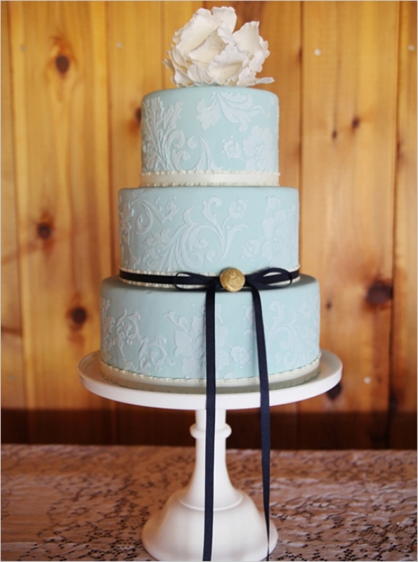 A light blue wedding cake with white patterns, a white sugar bloom on top, a black ribbon with a bow is a chic idea for a vintage infused wedding