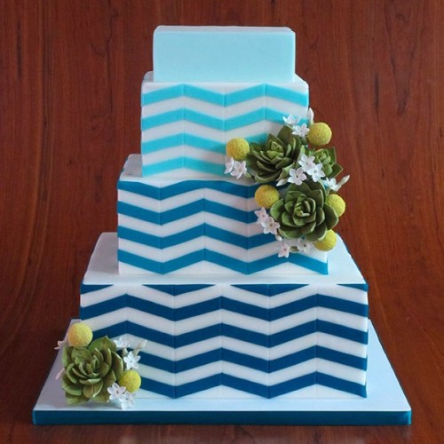 a square wedding cake with a navy, blue and turquoise tier with chevron prints, succulents and billy balls is a great idea for a mid-century modern wedding
