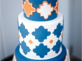 a beautiful wedding cake with blue and white tiers, with white and orange Moroccan-inspired patterns and a clock on top is a whimsical and lovely idea for a modern and bright wedding