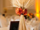 a simple rustic wedding centerpiece of wheat and orange roses for a refined rustic wedding