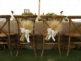 rustic wooden chairs accented with wheat and white blooms and ribbons for a rustic wedding