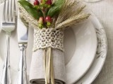 a grey napkin with a yarn napkin ring, wheat, greenery and berries is a pretty fall decoration for a wedding
