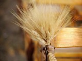 a wheat arrangement with a brown ribbon is a lovely decoration for aisle chairs, ideal for a rustic wedding