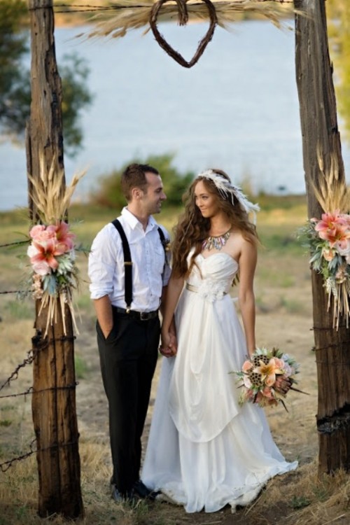 a rustic wedding arch decorated with wheat, pink blooms and greenery is a lovely and cozy idea