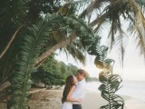 a giant curved wedding arch covered with palm leaves is a cool idea that looks all-natural