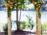 a wooden wedding arch decorated with greenery, bright blooms and with colorful flowers around