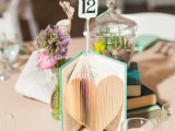 a vintage book with a heart cut out and a table number is a cool idea for a  vintage-inspired or book-loving wedding
