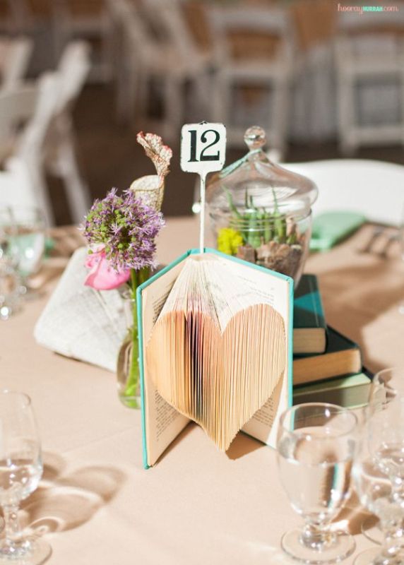 a vintage book with a heart cut out and a table number is a cool idea for a  vintage inspired or book loving wedding