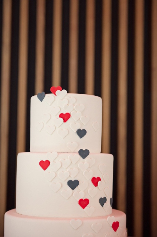 a neutral wedding cake decorated with graphite grey, red and white sugar hearts is a cool modern wedding idea