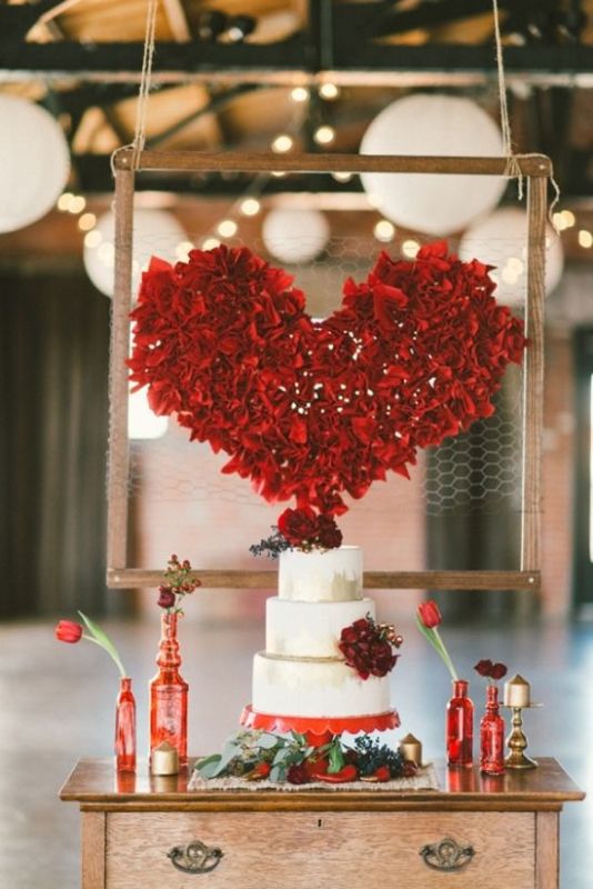 a gorgeous large red heart shaped decoration over the wedding cake is a fantastic decor idea to rock