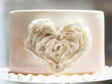 a blush watercolor wedding cake with a layered sugar heart on its side is a fresh and modern idea