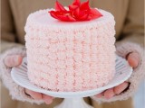 a pink buttercream onne tier wedding cake topped with bright red blooms on top is a cute idea