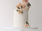 a tall textural one tier wedding cake with a tower of blush and neutral blooms on top is a very stylish idea
