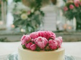 a stylish buttercream one tier wedding cake topped with bright pink peonies is a chic idea for a modern wedding