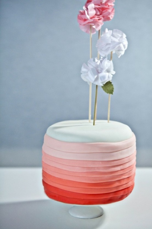 A colorful one tier wedding cake that seems to consist of multiple layers thanks to bright frosting and a cute topper