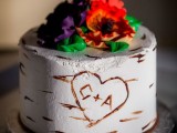 a rustic one tier wedding cake that imitates birch bark with its buttercream and sugar blooms for decor