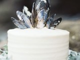 a textural buttercream single layer wedding cake topped with mussel shells is ideal for a seaside wedding