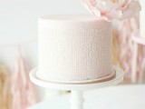 a blush wedding cake with lace decor and a single blush bloom on top is a very subtle and tender option