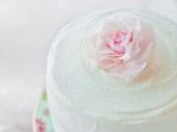 a one tier white buttercream wedding cake topped with a fresh pink bloom is a very beautiful spring option