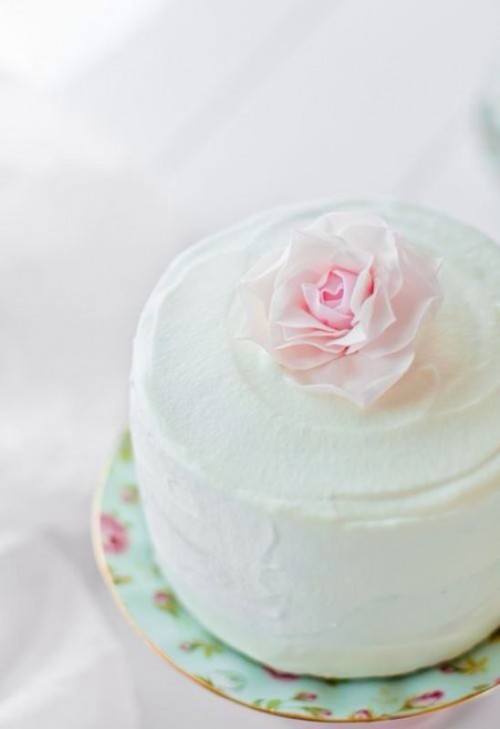 a one tier white buttercream wedding cake topped with a fresh pink bloom is a very beautiful spring option