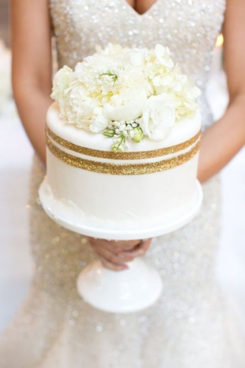 a white one tier wedding cake with gold glitter stripes and fresh neutral blooms is a very chic and elegant idea