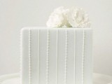 a white square wedding cake with fresh blooms on top is timeless classics for most of modern weddings