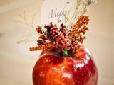 an apple wedding decoration – a red apple with berries and grasses and a table number is a lovely idea for a cool wedding in the fall