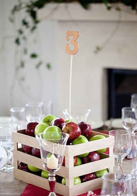 a crate with colorful apples and a table number is a lovely wedding centerpiece for a rustic wedding, and it can be done in minutes