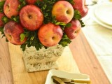 a rustic wedding centerpiece of a vase wrapped with bark, with apples and greenery is a lovely idea for a rustic wedding