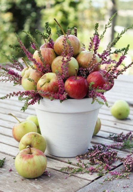 a white planter with apples and pink blooms is a cool wedding centerpiece that will fit a rustic wedding