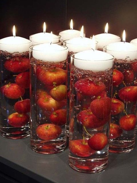 tall vases filled with apples and a floating candle on top are amazing as wedding decorations or favors
