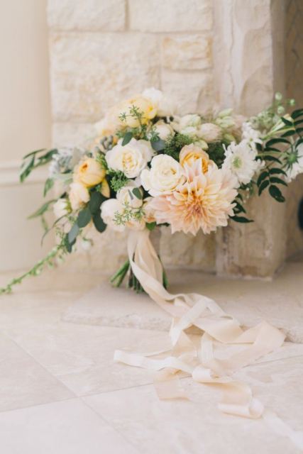 a delicate and subtle wedding bouquet of blush and white blooms and greenery and blush silk ribbons is a beautiful idea for a spring or summer wedding