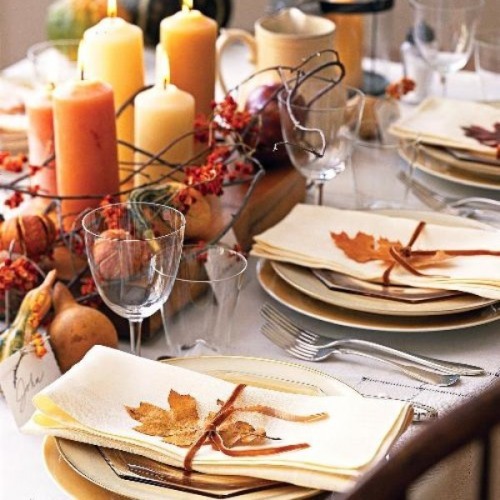 a neutral and organic wedding tablescape with earthy-colored candles, nuts, gourds and fall leaves that accent each place setting is very cozy and lovely
