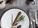 a beautiful organic fall wedding tablescape with grey linens, burlap, feathers, nuts and greenery plus metal mugs is cool and easy