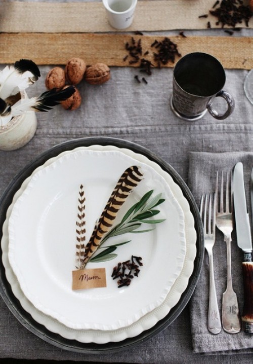 a beautiful organic fall wedding tablescape with grey linens, burlap, feathers, nuts and greenery plus metal mugs is cool and easy