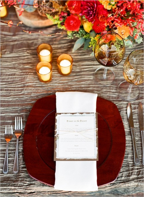 a pretty and bright fall wedding tablescape with a silver tablecloth, super bold floral arrangements, candles, a rich-stained wooden charger and elegant cutlery is all-cool