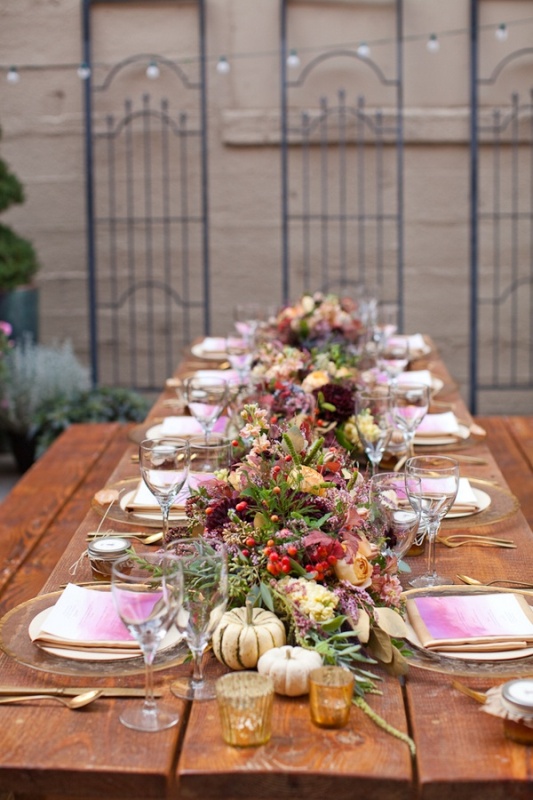 An amazing bold fall wedding tablescape with brigth fall blooms, greenery, berries, gourds, pumpkins, tie dye napkins and gold cutlery is very cool