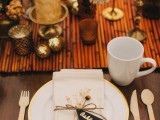 a glam fall wedding tablescape with a bamboo table runner, candles, dried flowers, Christmas ornaments, wooden cutlery for a sustainable touch