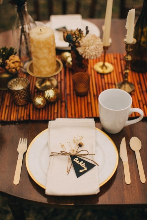 a glam fall wedding tablescape with a bamboo table runner, candles, dried flowers, Christmas ornaments, wooden cutlery for a sustainable touch
