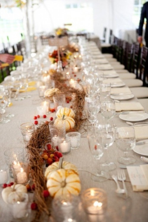 a chic fall wedding tablescape with pumpkins, berries, vines, candles and neutral linens, neutral chargers and plates