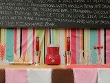 a colorful retro ice cream bar with a bright striped backdrop, strawberries, cones and an oversized chalkboard sign