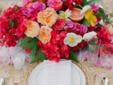 a bold tropical wedding tablescape in neutrals, with a woven charger and a bold floral centerpiece with citrus and fruits