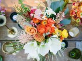 a colorful tropical wedding tablescape with a super bold floral centerpiece and tropical leaves, candles and colored glasses