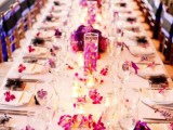 a bold white and purple wedding tablescape with bold purple blooms and napkins, candles and white linens is very elegant and refined